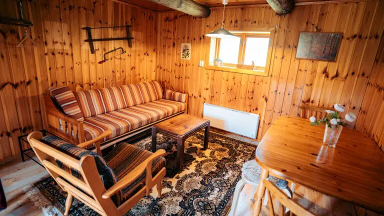 gemütlicher Innenraum einer Holzhütte mit gestreiftem Sofa und Esstisch