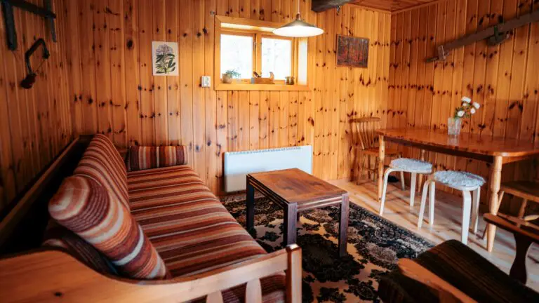 Gemütliches Inneres einer Holzfällerhütte mit Holzwänden und gestreiftem Sofa