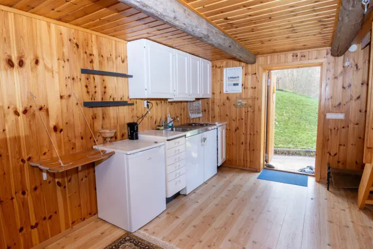 Gemütliches Inneres einer Holzfällerhütte mit kleiner Küche und Holzwänden