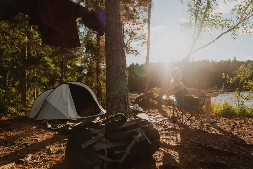 person relaxing at a campsite by a lake at sunset