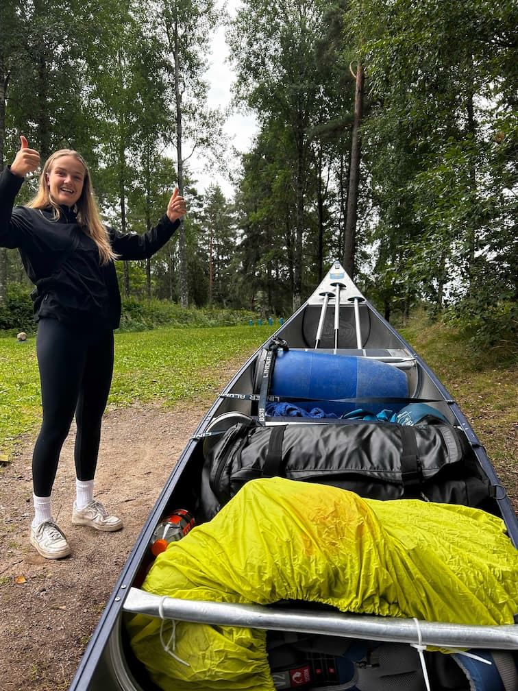 Participante heureuse avec son canoë rempli de ses affaires.